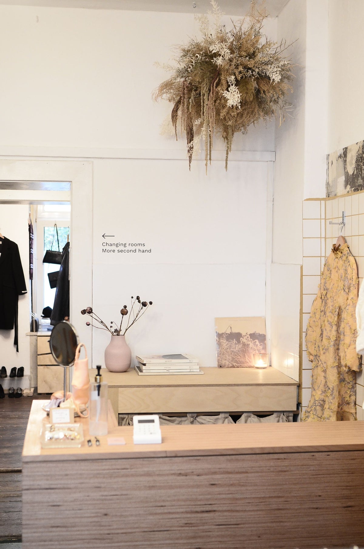A boutique checkout counter with a floral installation overhead