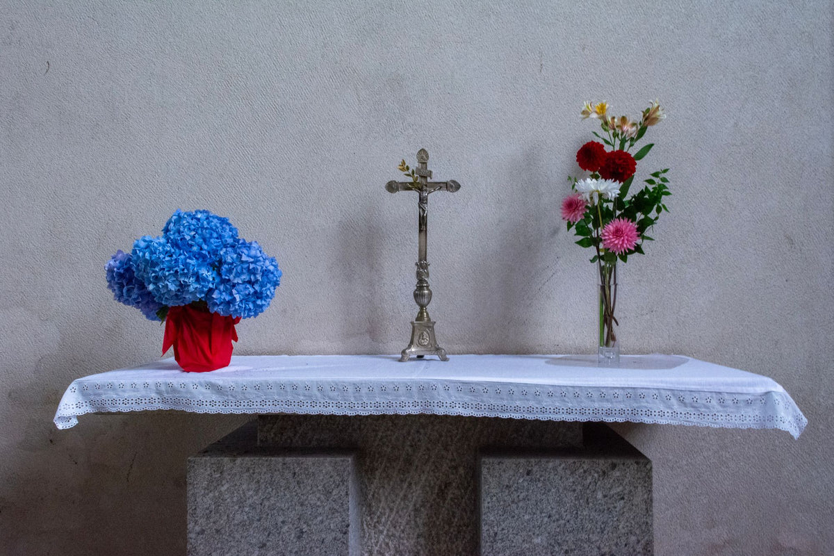 A simple altar with a brass cross and fresh hydrangeas