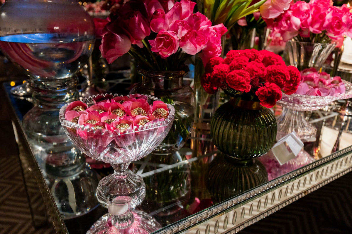 Pink roses in glass vessels on a mirrored console