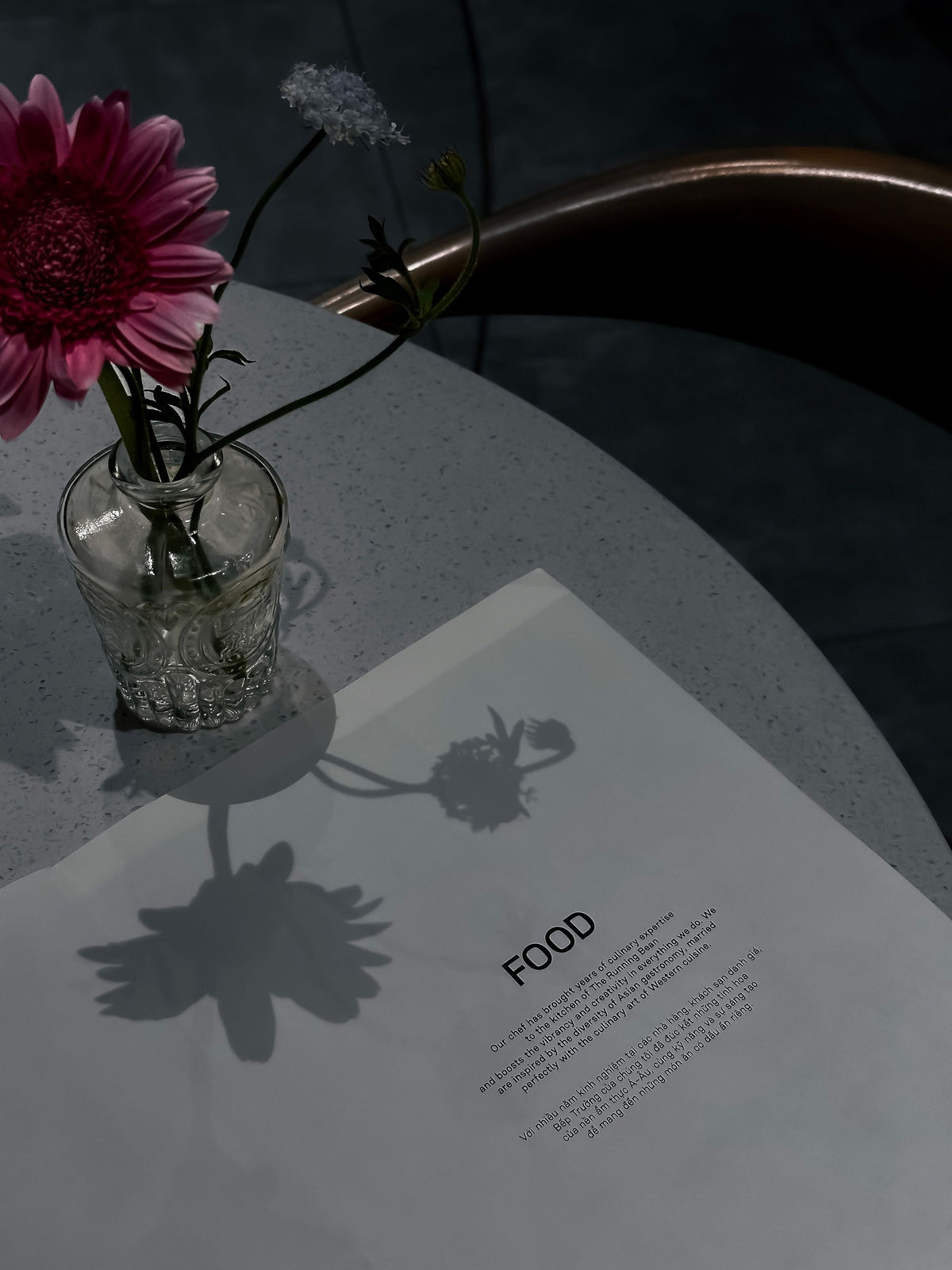A fresh gerbera in a small vase on a restaurant table