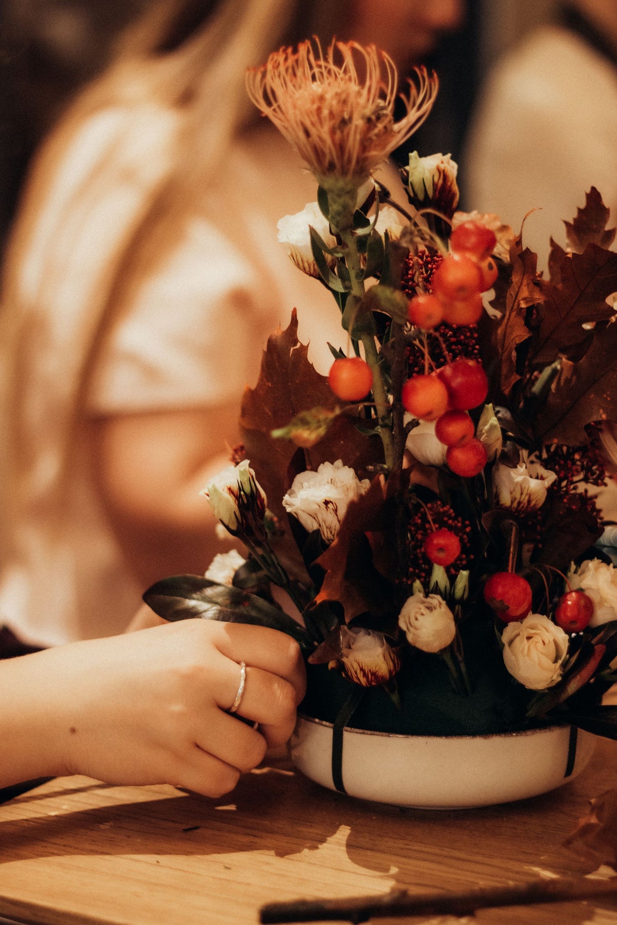 A seasonal arrangement with protea, berries, and cream roses