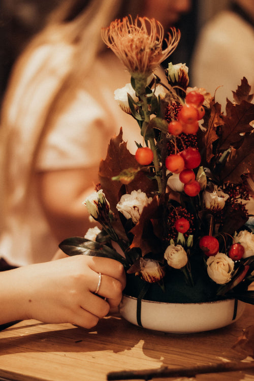 A seasonal arrangement with protea, berries, and cream roses